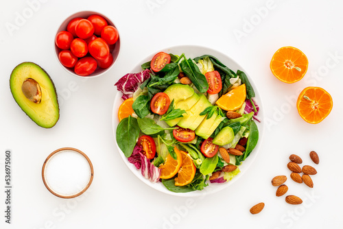 Fresh green salad with avocado and tomatoes, top view