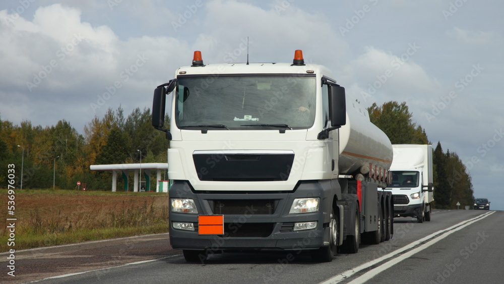 White semi truck fuel tanker drive on suburban highway road at autumn day, front view, ADR cargo transportation logistics in Europe