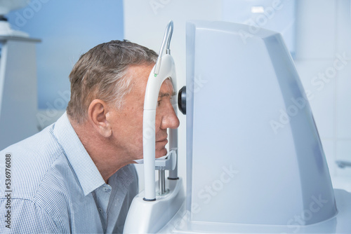 Fotografia an elderly man on a computer tomograph does a retinal tomography in the oculist'
