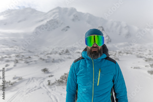 Man with ski glasses, preparing for winter skiing in snowy mountains.