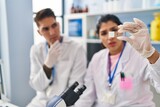 Man and woman scientists partners analysing sample at laboratory