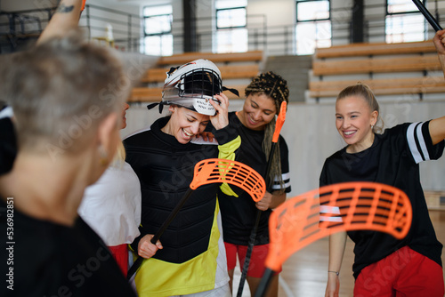 Foto Group of young and old cheerful women, floorball team players, in gym cebrating victory