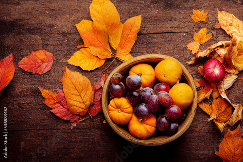 Autumn background from fallen leaves, berries and pumpkins on an old wooden table. Halloween day concept.