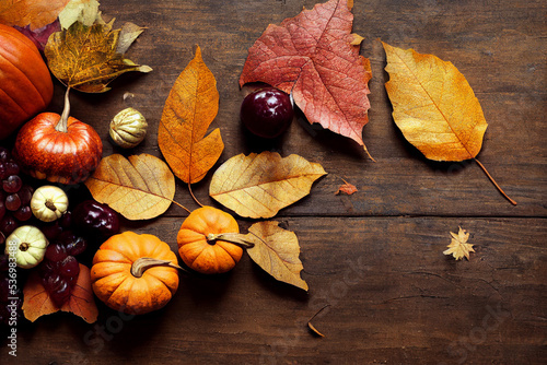 Autumn background from fallen leaves, berries and pumpkins on an old wooden table. Halloween day concept.