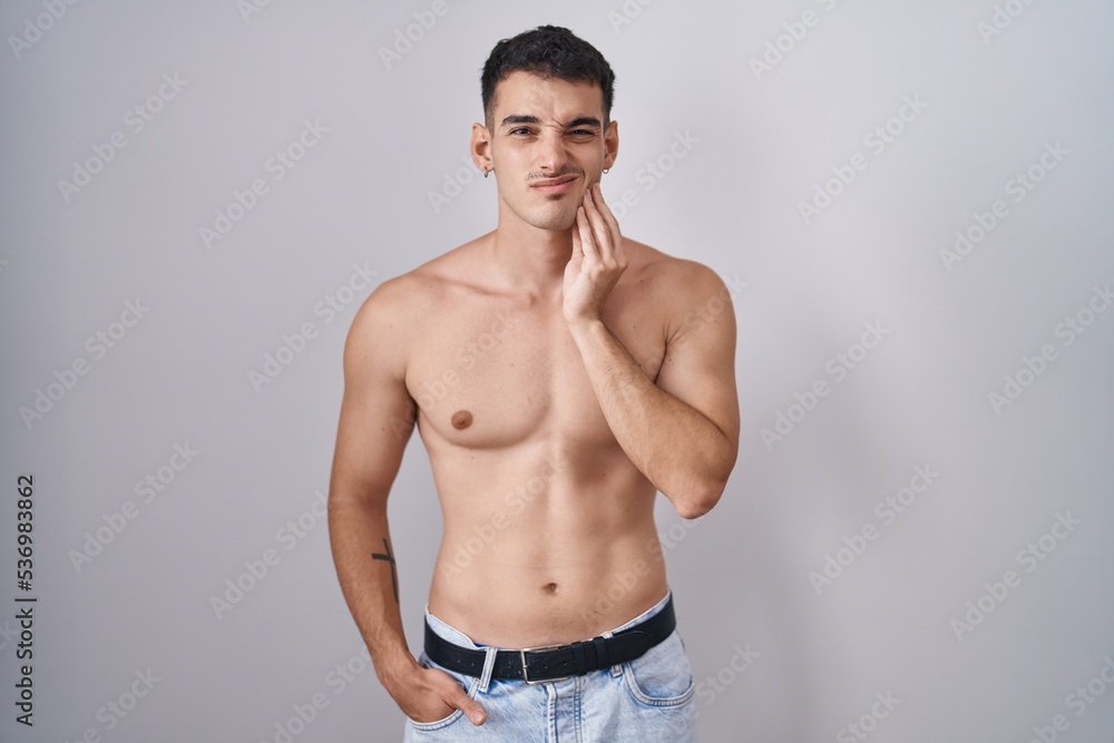 Handsome hispanic man standing shirtless touching mouth with hand with painful expression because of toothache or dental illness on teeth. dentist concept.