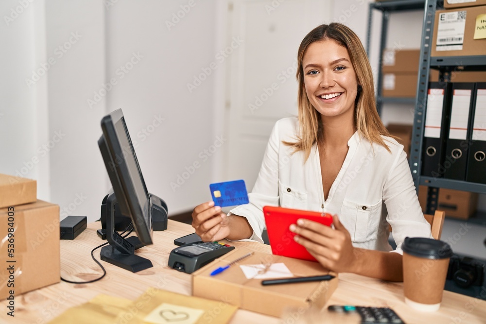 Young hispanic woman ecommerce business worker using touchpad and credit card at office Young hispanic woman ecommerce business worker using touchpad and credit card at office