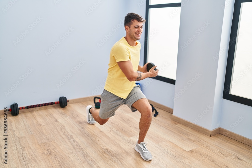 Fototapeta premium Young hispanic man using weight training at sport center