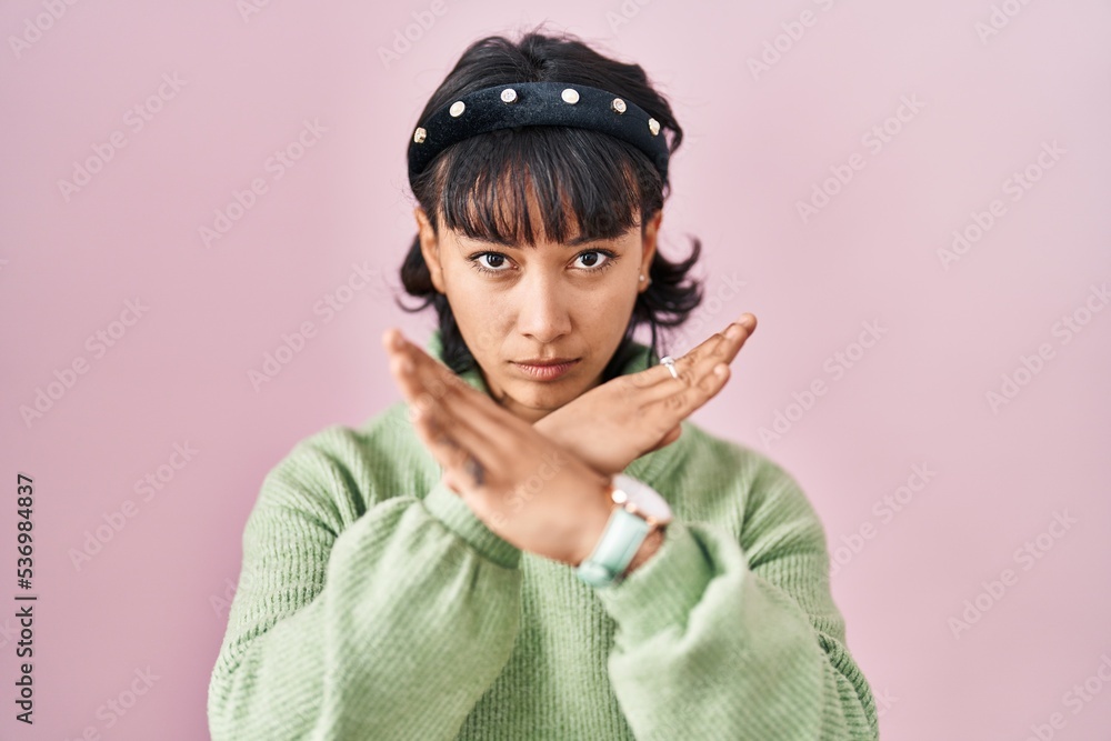 Young beautiful woman standing over pink background rejection expression crossing arms doing negative sign, angry face Young beautiful woman standing over pink background rejection expression crossing arms doing negative sign, angry face