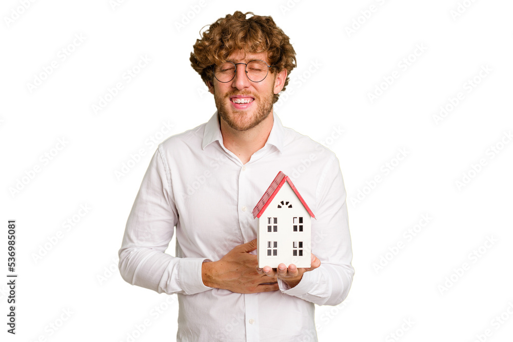 Business caucasian man holding toy house isolated on white background laughing and having fun. Business caucasian man holding toy house isolated on white background laughing and having fun.