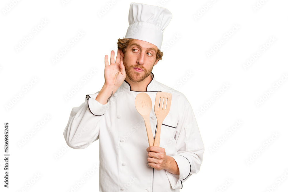 Young cook man isolated on white background trying to listening a gossip. Young cook man isolated on white background trying to listening a gossip.