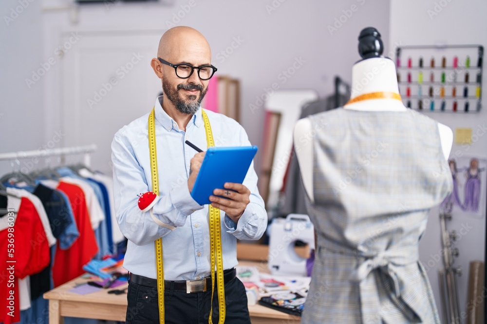 Young bald man tailor smiling confident drawing on touchpad at tailor shop Young bald man tailor smiling confident drawing on touchpad at tailor shop