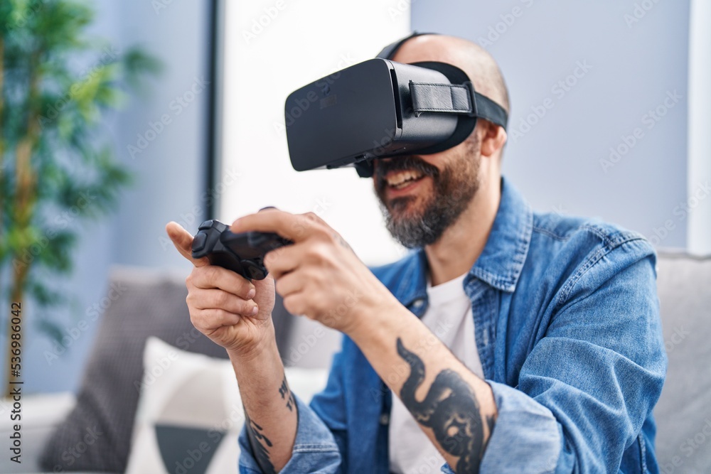 Young bald man playing video game using virtual reality glasses at home Young bald man playing video game using virtual reality glasses at home