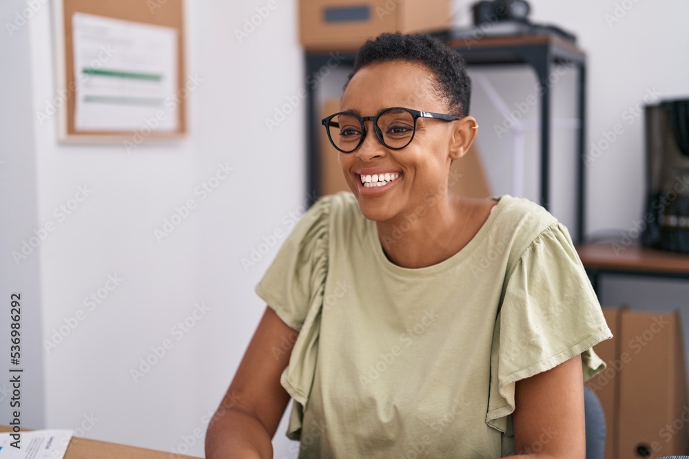 Fototapeta premium African american woman business worker smiling confident sitting on table at office