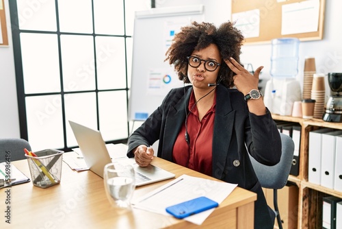 Foto African american woman with afro hair working at the office wearing operator headset shooting and killing oneself pointing hand and fingers to head like gun, suicide gesture
