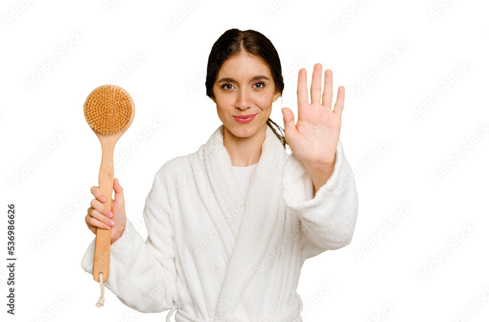 Young caucasian woman holding a shower brush isolated standing with outstretched hand showing stop sign, preventing you. Young caucasian woman holding a shower brush isolated standing with outstretched hand showing stop sign, preventing you.