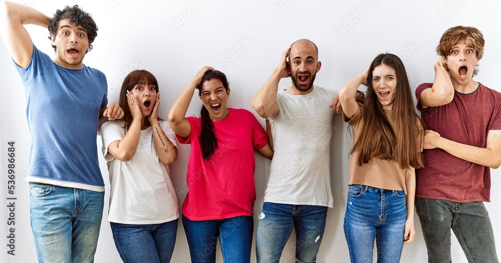 Group of young friends standing together over isolated background crazy and scared with hands on head, afraid and surprised of shock with open mouth Group of young friends standing together over isolated background crazy and scared with hands on head, afraid and surprised of shock with open mouth