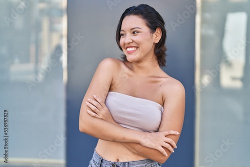 Young hispanic woman standing with arms crossed gesture at street