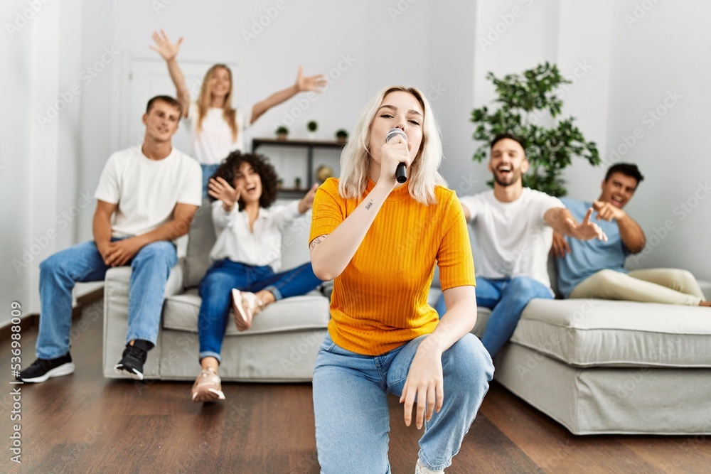 Group of young friends having party singing song using microphone at home. Group of young friends having party singing song using microphone at home.