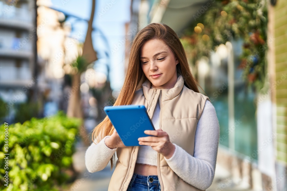 Young blonde woman smiling confident using touchpad at street