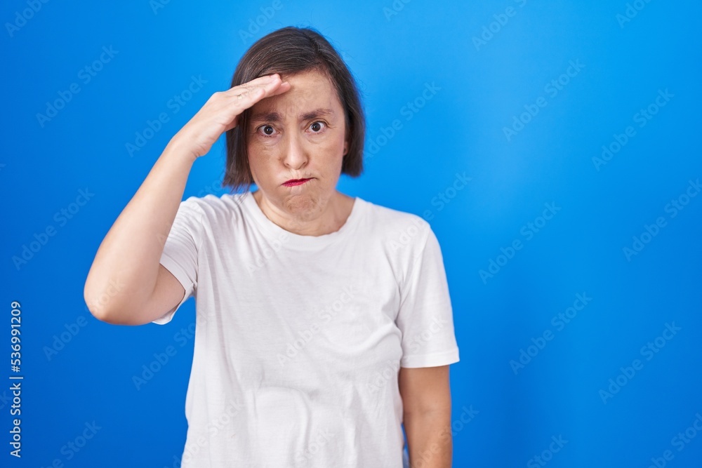 Middle age hispanic woman standing over blue background worried and stressed about a problem with hand on forehead, nervous and anxious for crisis Middle age hispanic woman standing over blue background worried and stressed about a problem with hand on forehead, nervous and anxious for crisis