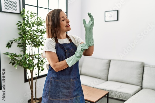 Quadro su tela Middle age hispanic woman working as housekeeper at home