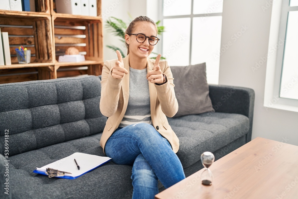 Young woman working at consultation office pointing fingers to camera with happy and funny face. good energy and vibes. Young woman working at consultation office pointing fingers to camera with happy and funny face. good energy and vibes.