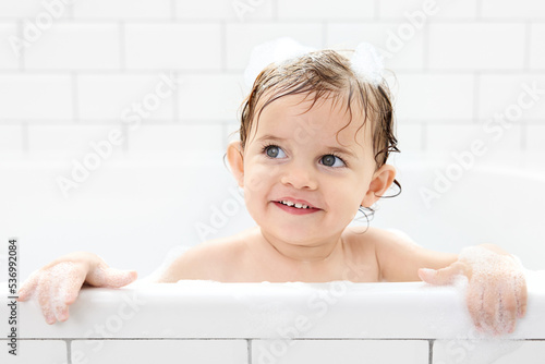 Happy toddler with wet hair in bathtub