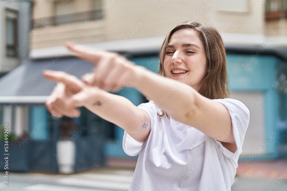 Young woman smiling confident pointing with fingers at street