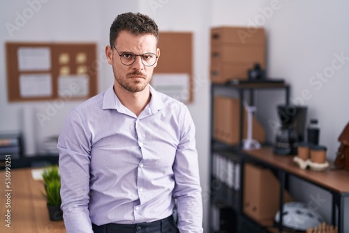Young hispanic man at the office skeptic and nervous, frowning upset because of problem. negative person.