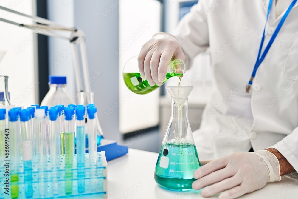 Young hispanic man scientist measuring liquid at laboratory Young hispanic man scientist measuring liquid at laboratory
