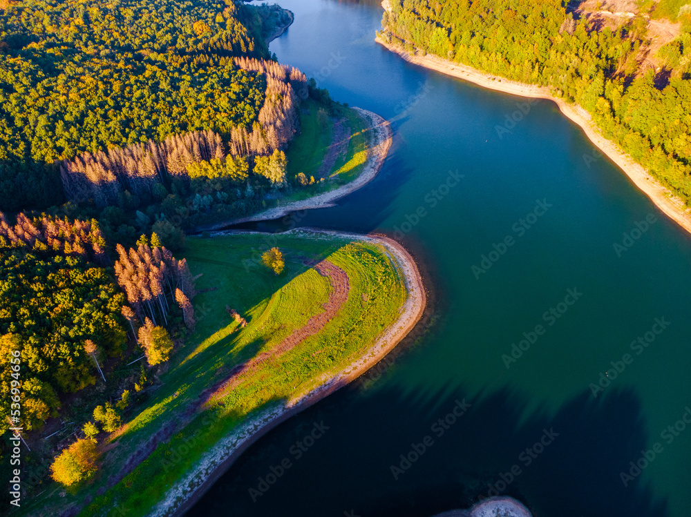 Aerial view of coast of natural lake in autumn with beautiful tree colours and reflections