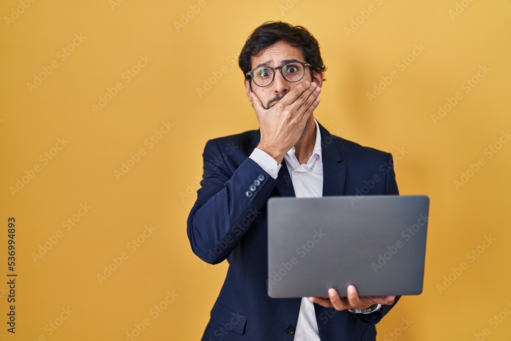 Handsome latin man working using computer laptop shocked covering mouth with hands for mistake. secret concept. Handsome latin man working using computer laptop shocked covering mouth with hands for mistake. secret concept.