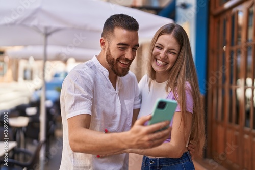 Man and woman couple smiling confident using smartphone at street