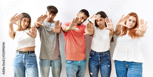 Group of young friends standing together over isolated background doing frame using hands palms and fingers, camera perspective