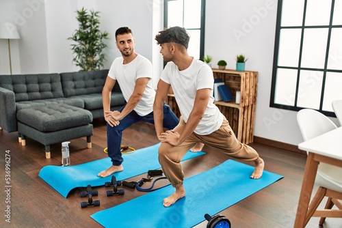 Two hispanic men couple smiling confident stretching at home