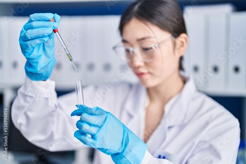 Chinese woman scientist pouring liquid on test tube at laboratory