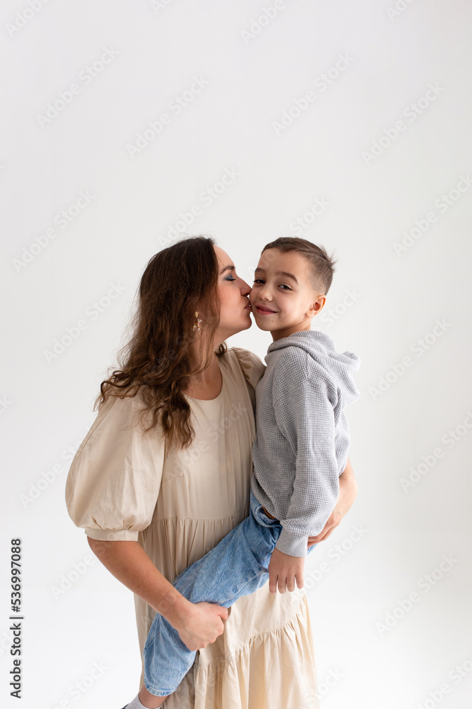 Boy preschooler and mother smile and hug on gray background in photo studio Boy preschooler and mother smile and hug on gray background in photo studio