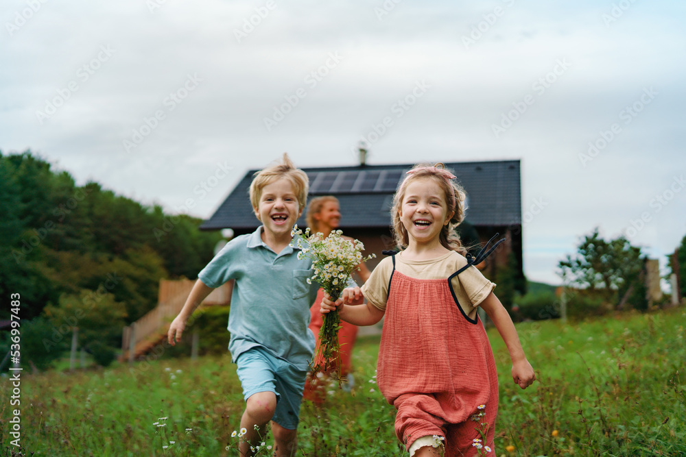 Obraz premium Happy family running near their house with solar panels. Alternative energy, saving resources and sustainable lifestyle concept.
