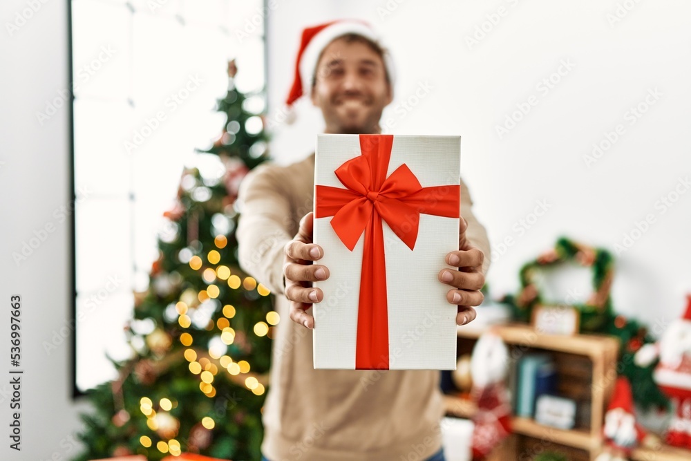 Young hispanic man smiling confident holding christmas gift at home Young hispanic man smiling confident holding christmas gift at home