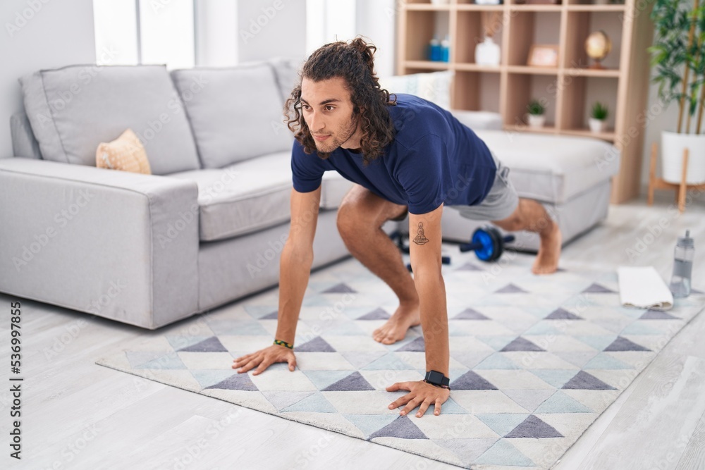 Fototapeta premium Young hispanic man training yoga at home