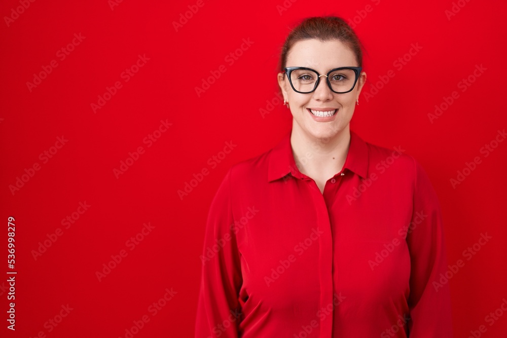Young hispanic woman with red hair standing over red background with a happy and cool smile on face. lucky person. Young hispanic woman with red hair standing over red background with a happy and cool smile on face. lucky person.