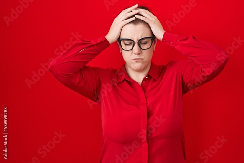 Young hispanic woman with red hair standing over red background suffering from headache desperate and stressed because pain and migraine. hands on head. © Krakenimages.com