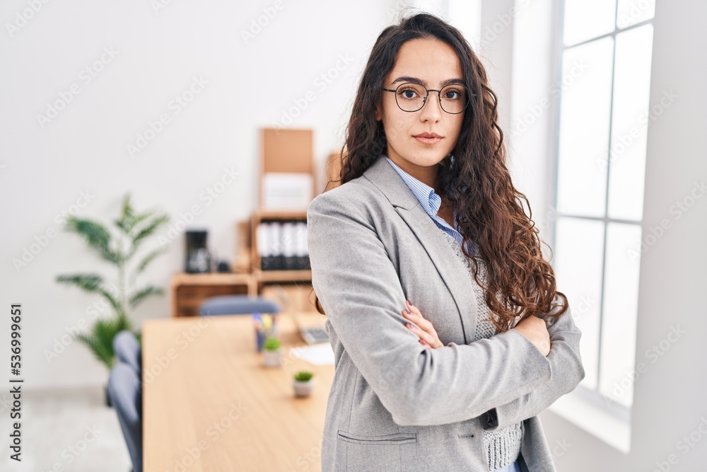 Young hispanic woman business worker standing with arm and serious expressions crossed gesture at office Young hispanic woman business worker standing with arm and serious expressions crossed gesture at office