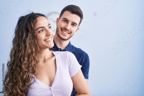 Young hispanic couple hugging each other standing at home