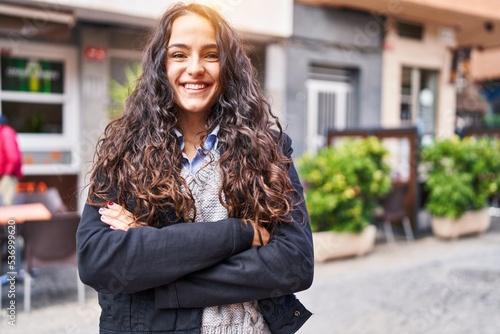 Young hispanic woman smiling confident standing with arms crossed gesture at street