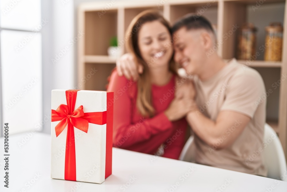 Man and woman mother and son sitting on table with gift at home Man and woman mother and son sitting on table with gift at home