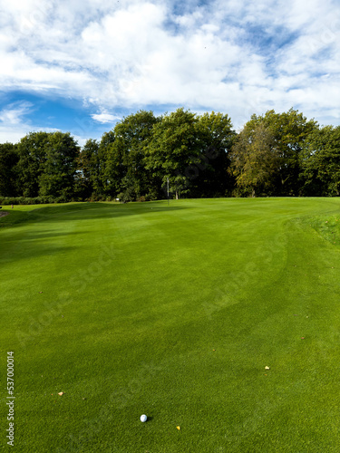 Golf course in the countryside with ball and flag in view