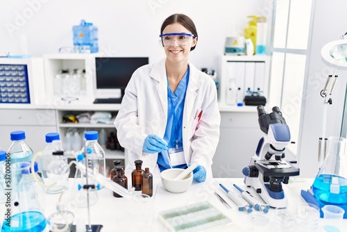 Young hispanic woman wearing scientist uniform working at laboratory