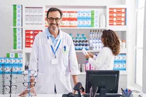 Man and woman pharmacists smiling confident working at pharmacy
