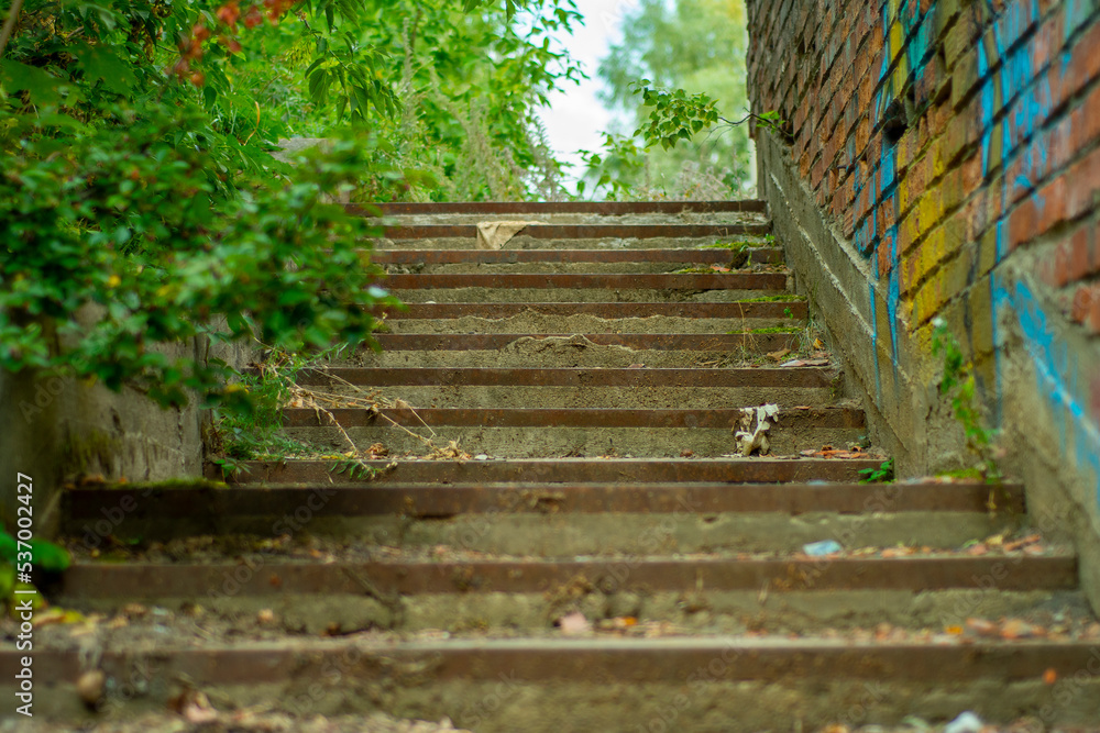 Close-up of a brick wall with remnants of color drawings and a concrete staircase in soft focus. Backdrop on the topic of a disadvantaged area and abandoned quarters of the city.